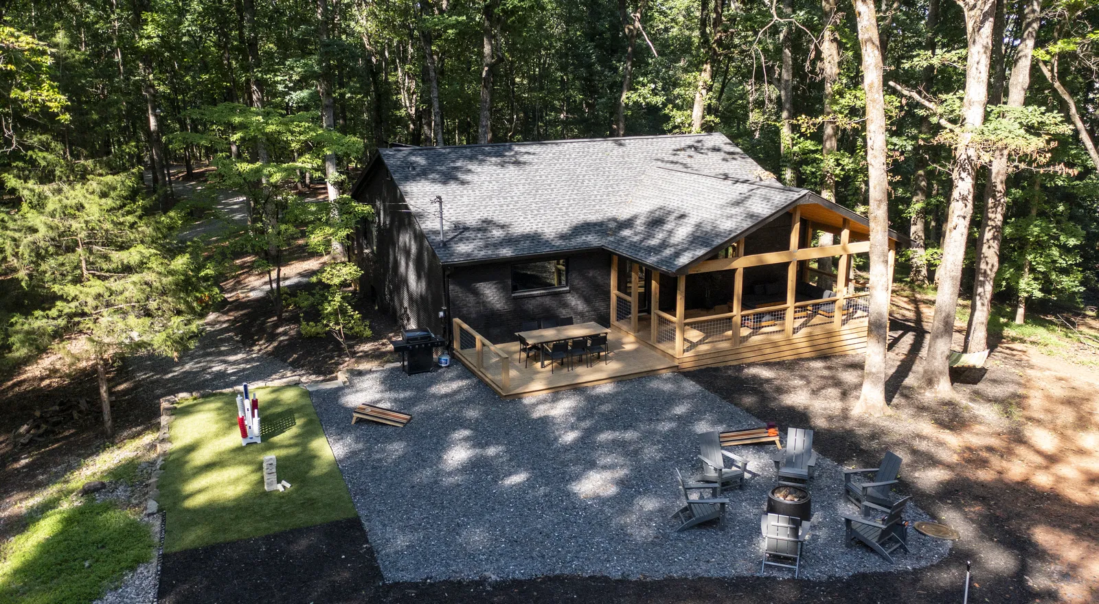 Aerial view of Adventure Acres cabin surrounded by North Georgia forest, with fire pit and lawn games
