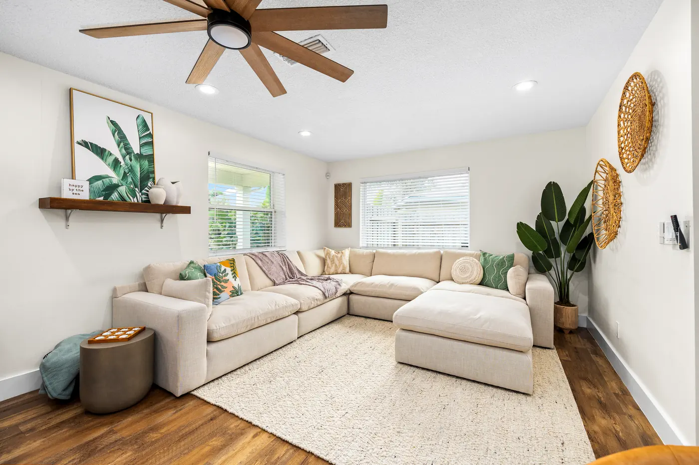 Coastal living room with sectional sofa, woven wall decor, and natural light at Family Tides