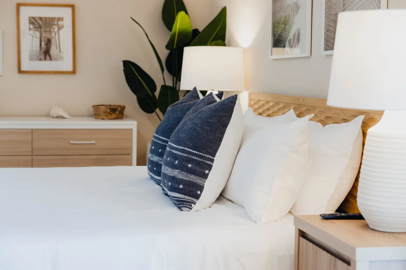 Close-up of a made bed with navy patterned throw pillows and layered white bedding at Kailani House