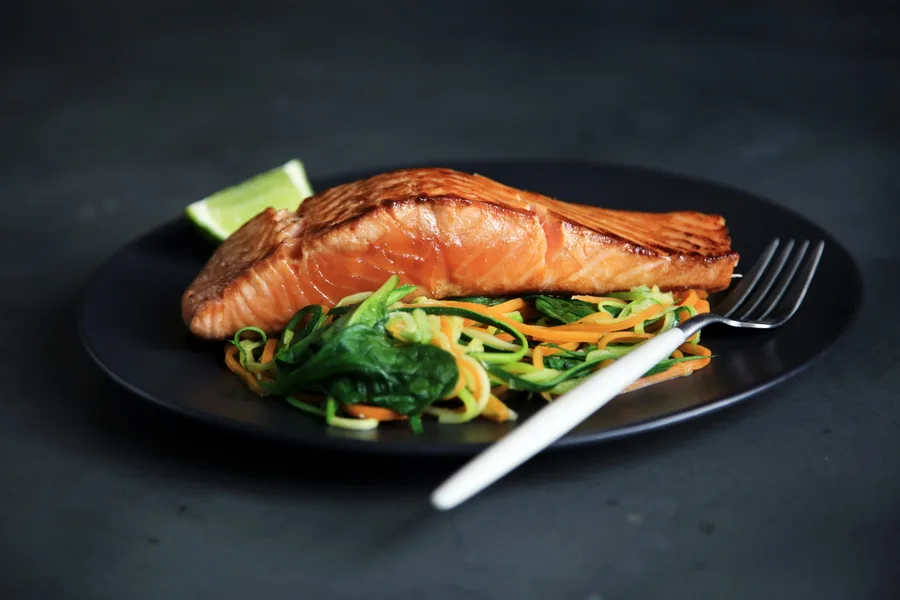 Seared salmon with vegetables on a black plate